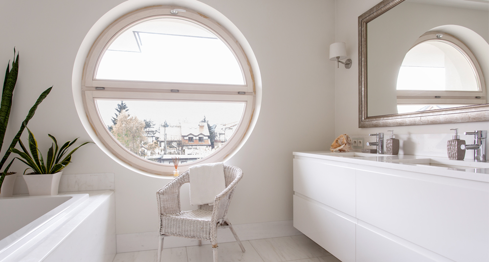 Badezimmer in beige mit einem Spiegel Riesiges rundes Fenster und eine rechteckiger Spiegel