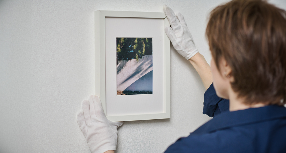 Weisser Bilderrahmen wird aufgehangen Bilderrahmen wird aufgehangen und mittig platziert