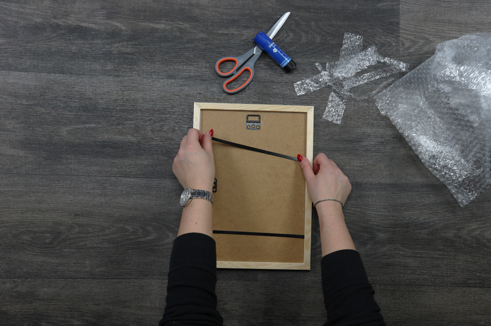 DIY Jahreskalender aus Luftpolsterfolie: Bilderrahmen schließen Holzbilderrahmen wird mit Rückwand und Metallfedern verschlossen