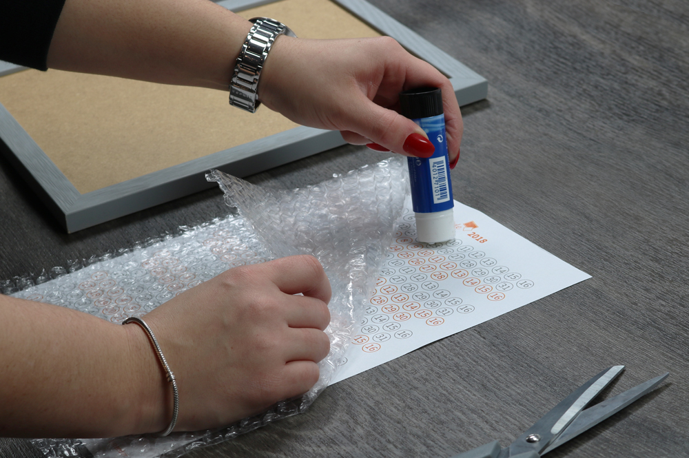 Kleber wird für DIY-Projekt auf Kalender aufgetragen