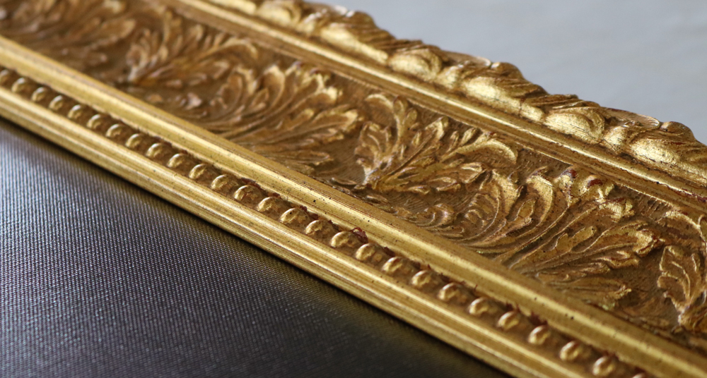 goldene Bilderrahmenleiste mit Gravur Detailaufnahme eines antiken Bilderrahmen in Gold