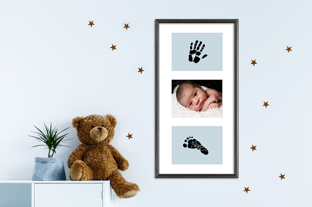 Handabdruck und Fußabdruck eines Babys in schwarzem Galerierahmen Baby Erinnerung: eingerahmt auf blauem Hintergrund