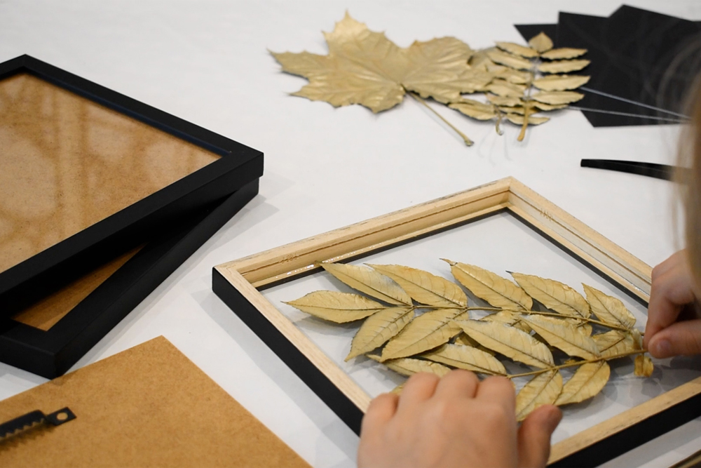 DIY Basteln mit Blättern - Blätter positionieren goldene Blätter werden für DIY-Projekt in Bilderrahmen positioniert
