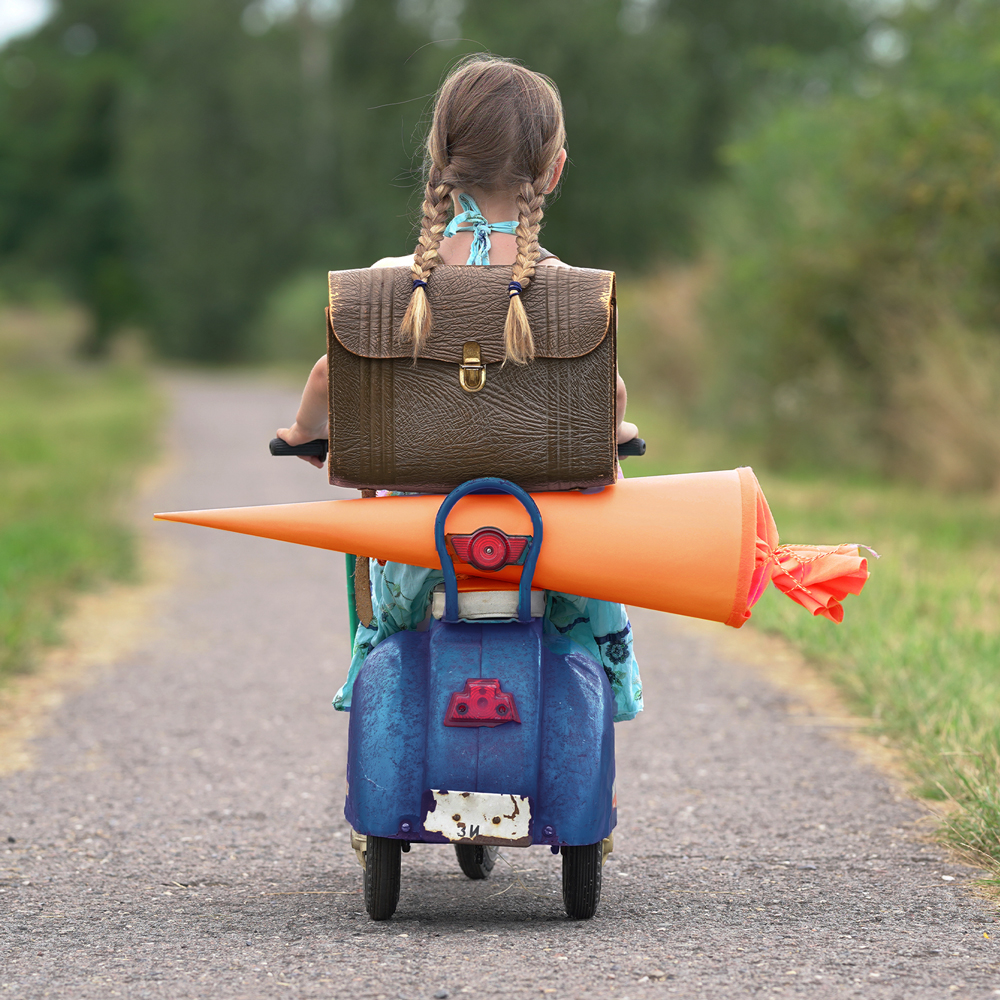 Mädchen fährt mit einem kleinen Moped  mit einer Zuckertüte