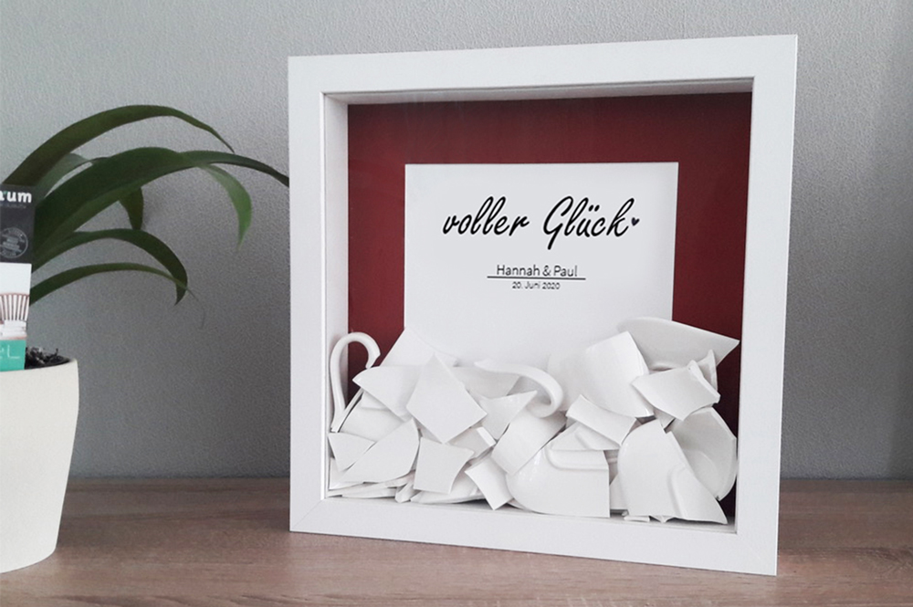 kreatives Hochzeitsgeschenk in weißem Rahmen Scherben eines Polterabends als Geschenk