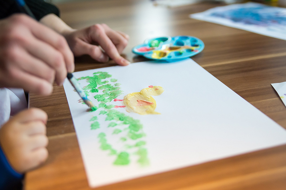 kreative Zeit mit Kindern - malen mit Pinseln Kind pinselt Bild eines Vogels