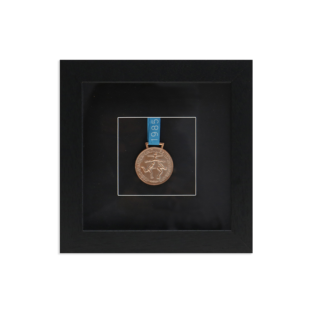 bronzene Medaille in schwarzem Objektrahmen aus Holz