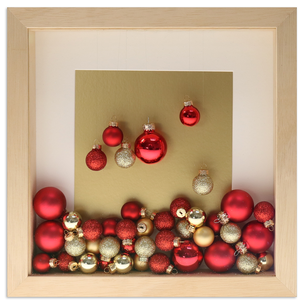 naturfarbener Objektrahmen gefüllt mit roten und goldenen Weihnachtskugeln