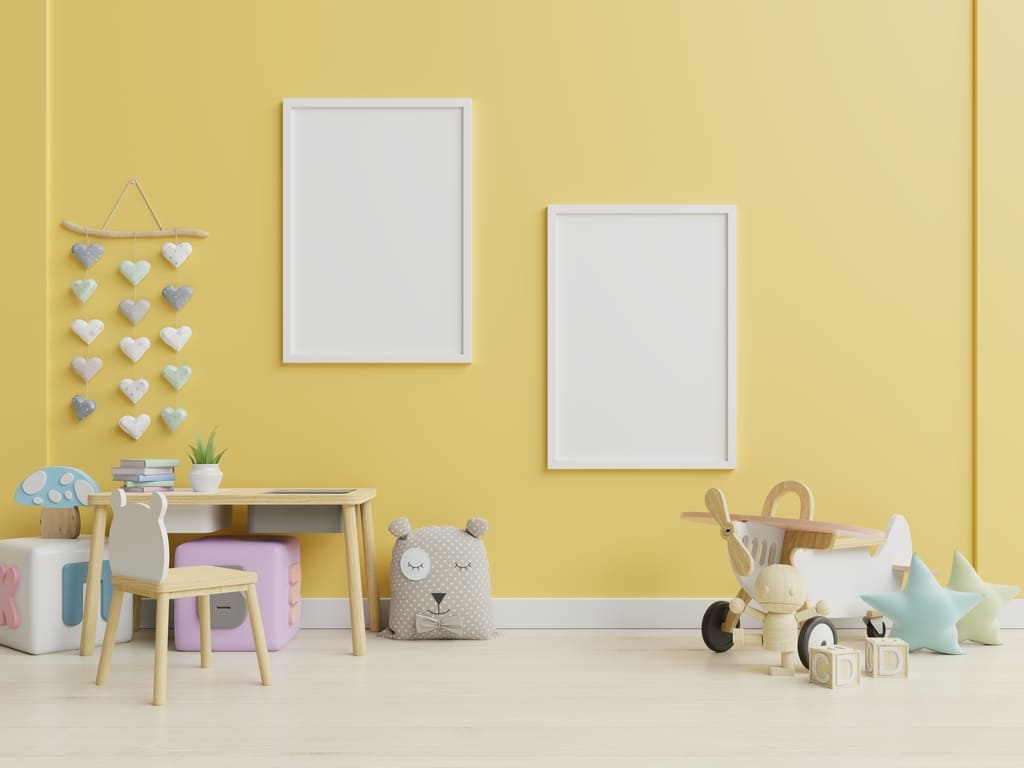 modernes Kinderzimmer in der Wandfarbe Gelb in Gelb gestrichenes Kinderzimmer mit Spielzeugen und weißen Bilderrahmen