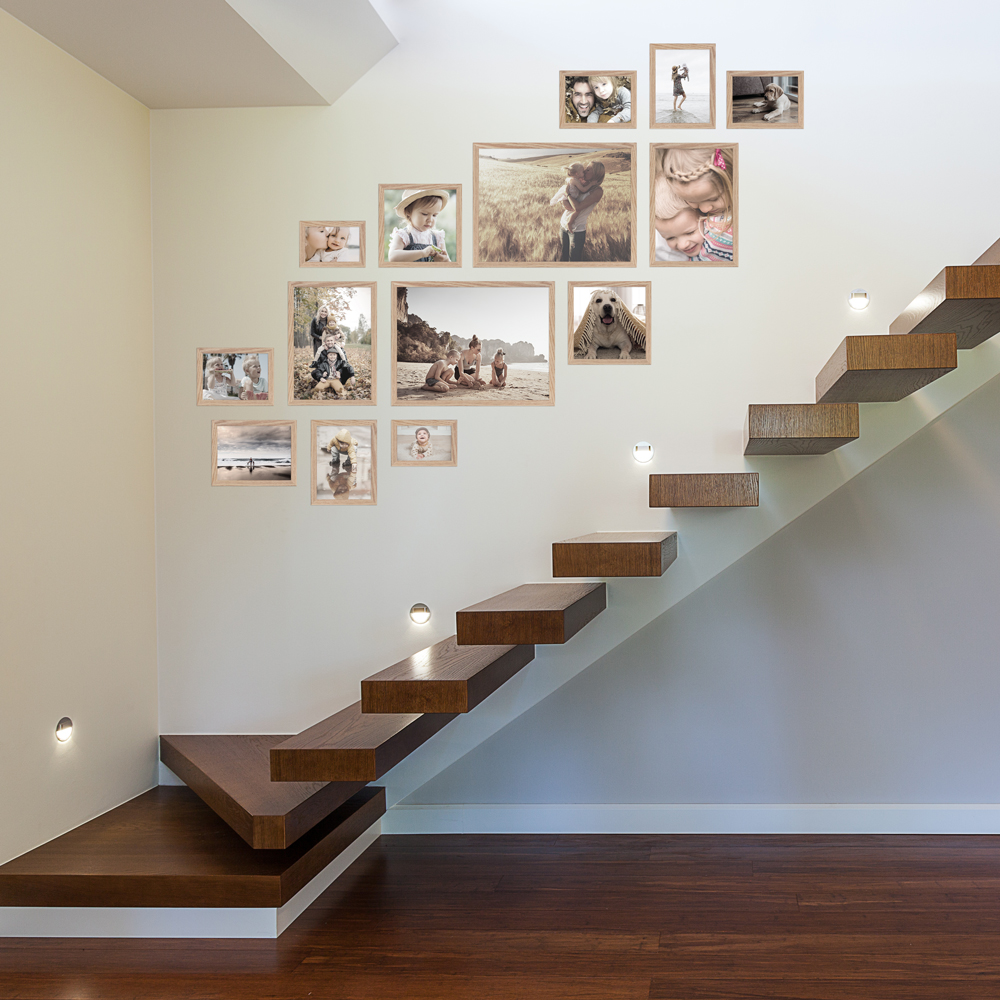 Bilderwand im Treppenhaus aus eichefarbenem 14er Bilderrahmen-Set